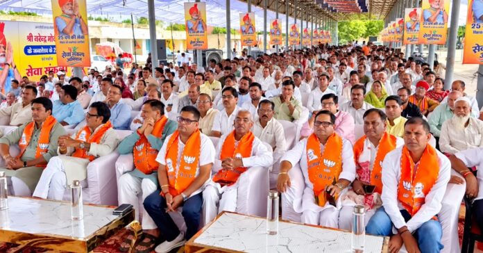 Covered Political Rally with Orange Banners Large चूरू कृषि उपज मंडी में सेवा ज्योति यात्रा एवं विकसित भारत संकल्प सभा में मौजूद भाजपा नेता और कार्यकर्ता